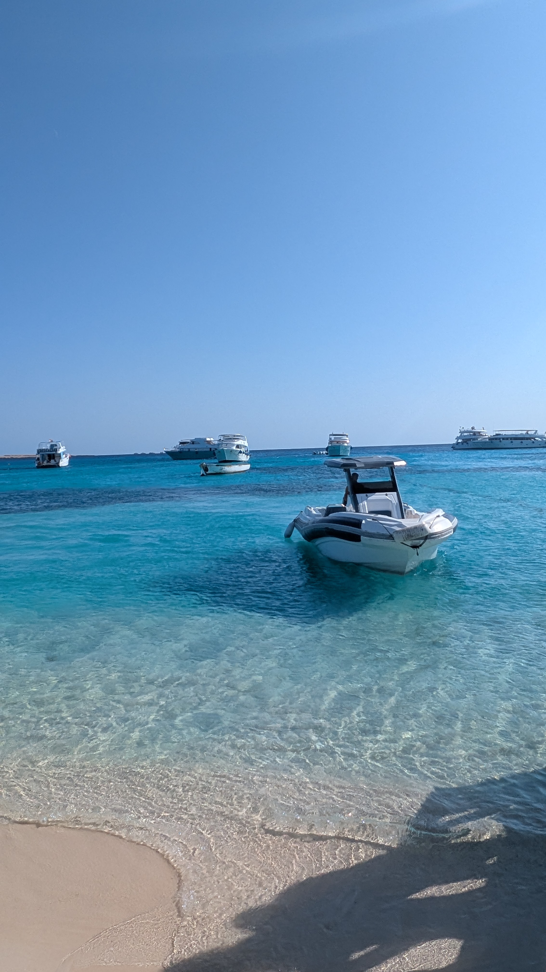 Speedboat in crystal-clear Red Sea water with yachts in the background